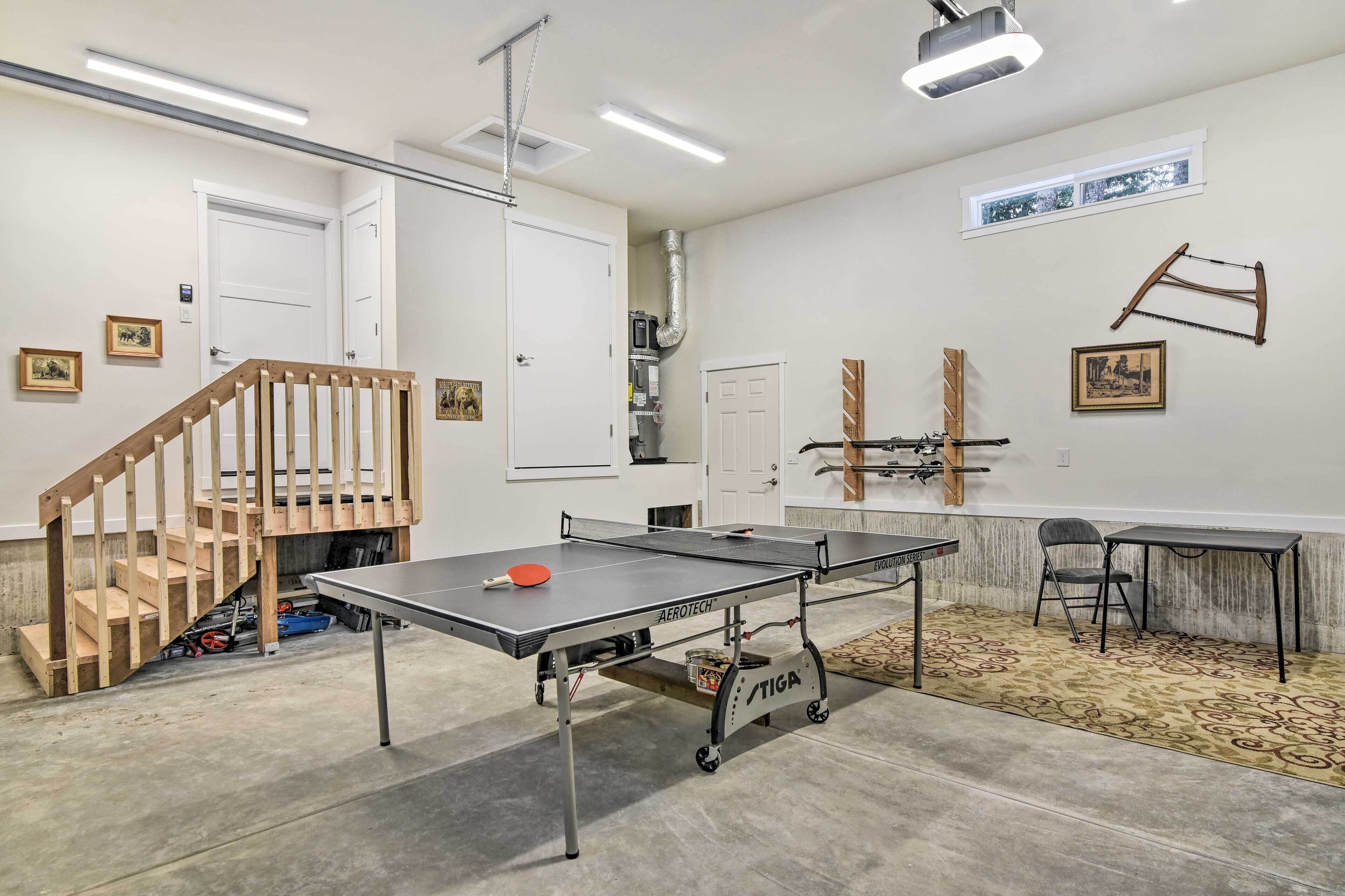 Une pièce spacieuse équipée d’une table de ping-pong, d’un escalier et d’une petite table avec des chaises.
