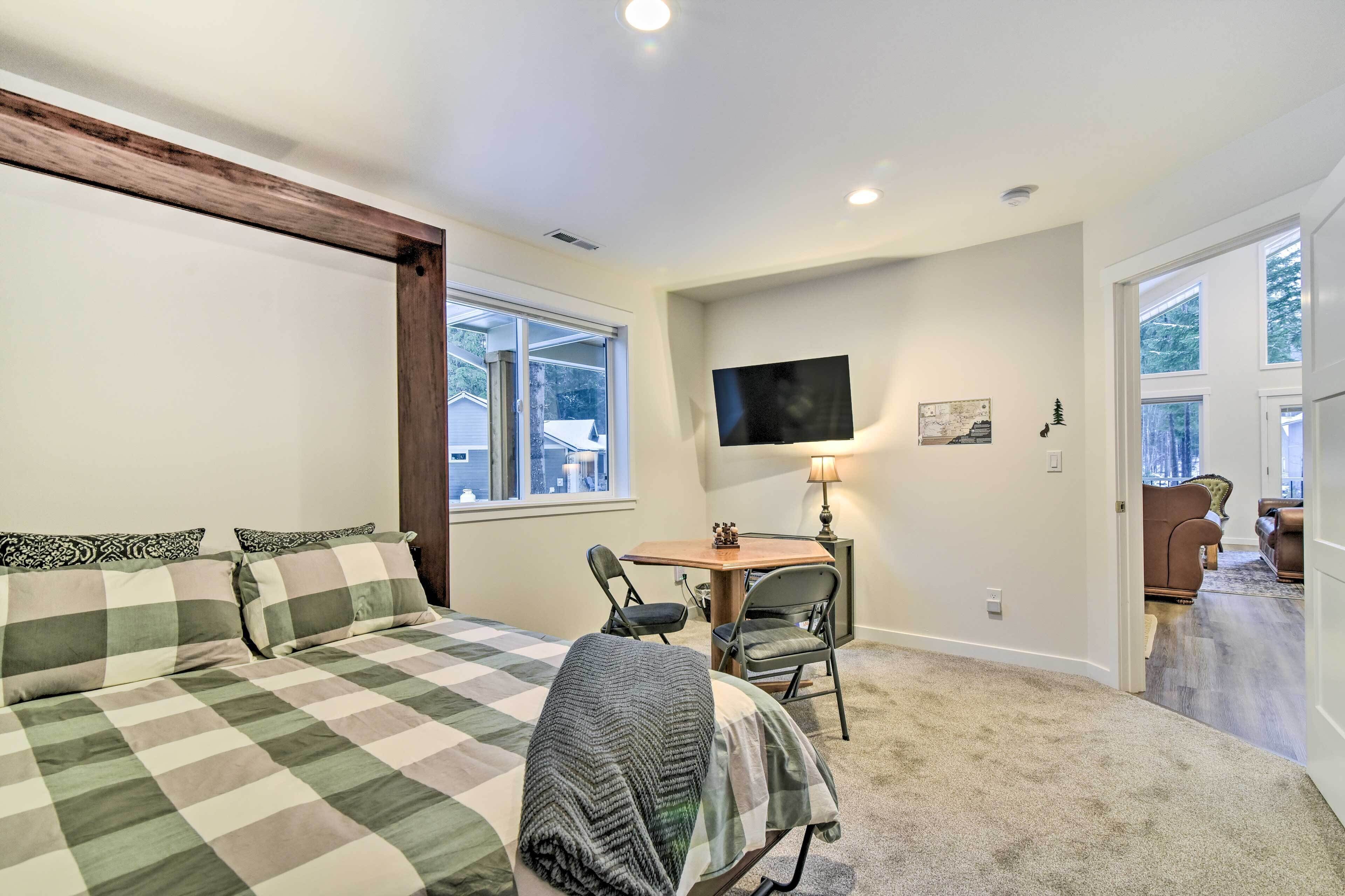 A bedroom with a bed, a desk, a chair, a TV, and a lamp.