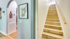 A hallway with a wooden staircase, framed artwork, and a vent. - < 5 Mi to Lake Desoto: Grand Hot Springs Home (Hot Springs Village)