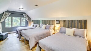 A bedroom with three beds, a wooden floor, a sloped ceiling, and a window with curtains. - < 5 Mi to Lake Desoto: Grand Hot Springs Home (Hot Springs Village)
