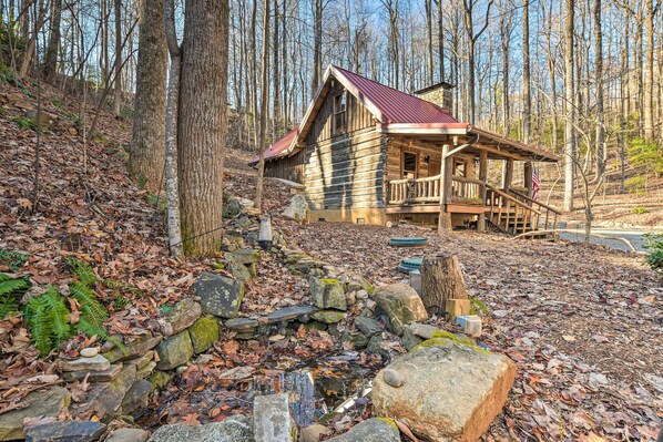 Une cabane rustique avec une façade en bois, une véranda et un toit en métal.