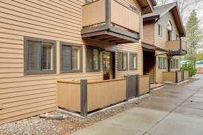 A two-story building with a wooden exterior, large windows with blinds, and a balcony on the upper floor. - Sunriver Vacation Rental w/ Community Hot Tub! (Bend)
