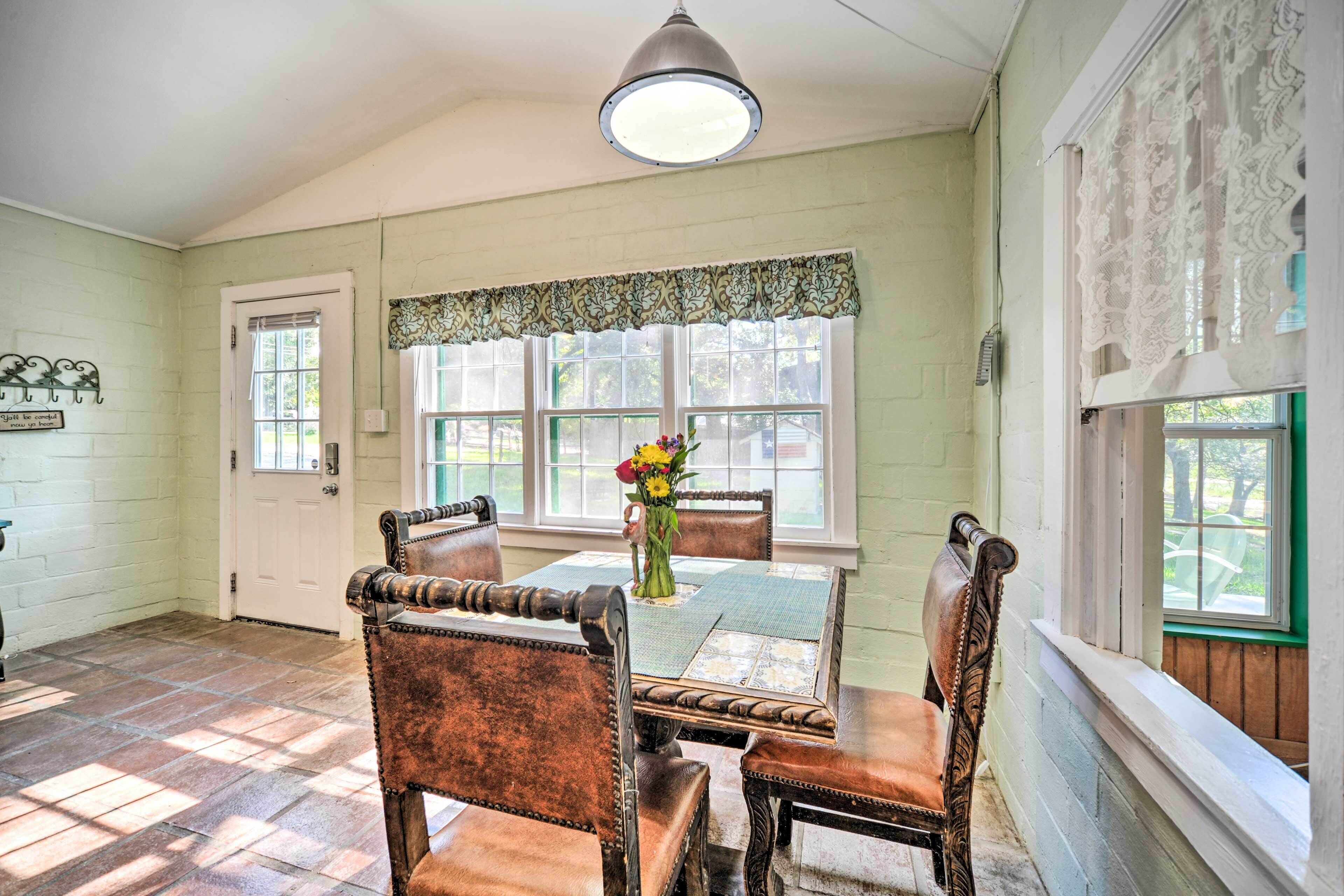 A dining area with a table set for four, surrounded by wooden chairs with leather upholstery.