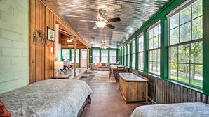 Un chalet rustique doté de deux lits, d’un coin repas et de grandes fenêtres offrant une vue sur l’extérieur.