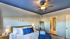 A bedroom with a bed, nightstand, lamp, ceiling fan, and a bathroom door. - Modern Poncha Springs Townhome w/ Mtn Views! (Salida)
