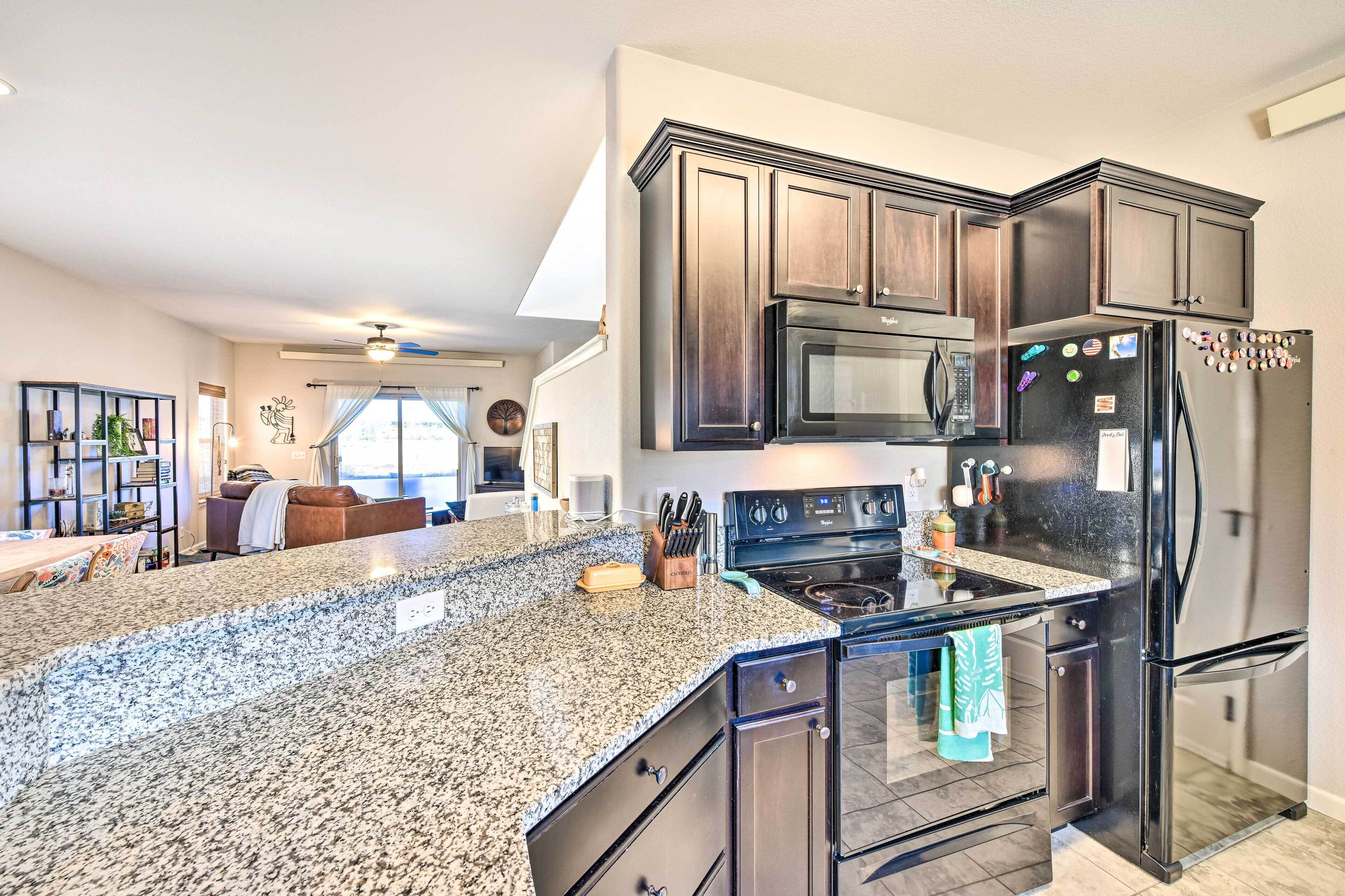 A modern kitchen with granite countertops, stainless steel appliances, and dark wood cabinetry.