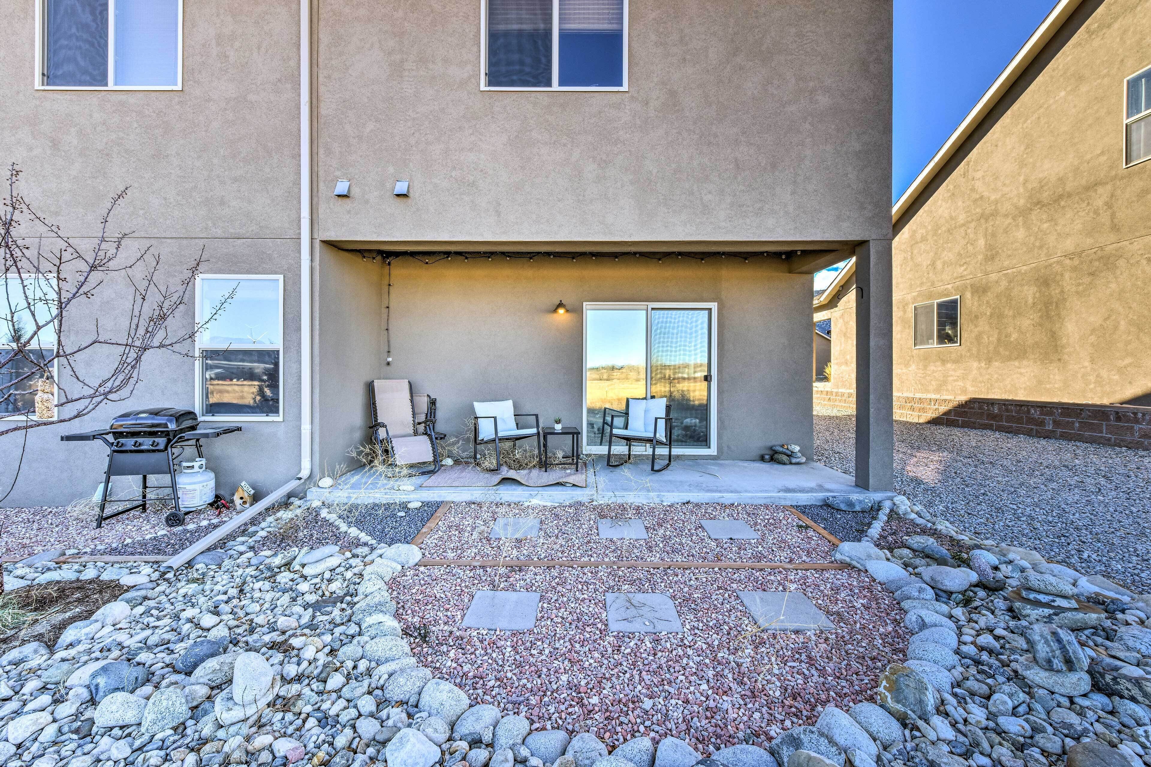 A patio area with a barbecue grill, outdoor seating, and a view of the sunset.