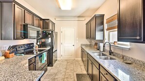 A modern kitchen with dark wood cabinets, granite countertops, stainless steel appliances, and a large window above the sink. - Modern Poncha Springs Townhome w/ Mtn Views! (Salida)