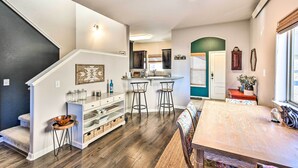 A modern kitchen with a central island, bar stools, and a dining table. - Modern Poncha Springs Townhome w/ Mtn Views! (Salida)