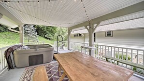 A covered outdoor area with a wooden table, a hot tub, and string lights. - Settlers Mountain Retreat: On-site Hikes & Views! (Bryson City)