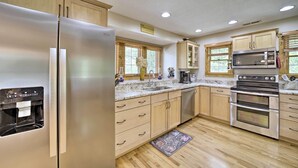 A modern kitchen with stainless steel appliances, wooden cabinets, and a built-in oven. - Settlers Mountain Retreat: On-site Hikes & Views! (Bryson City)