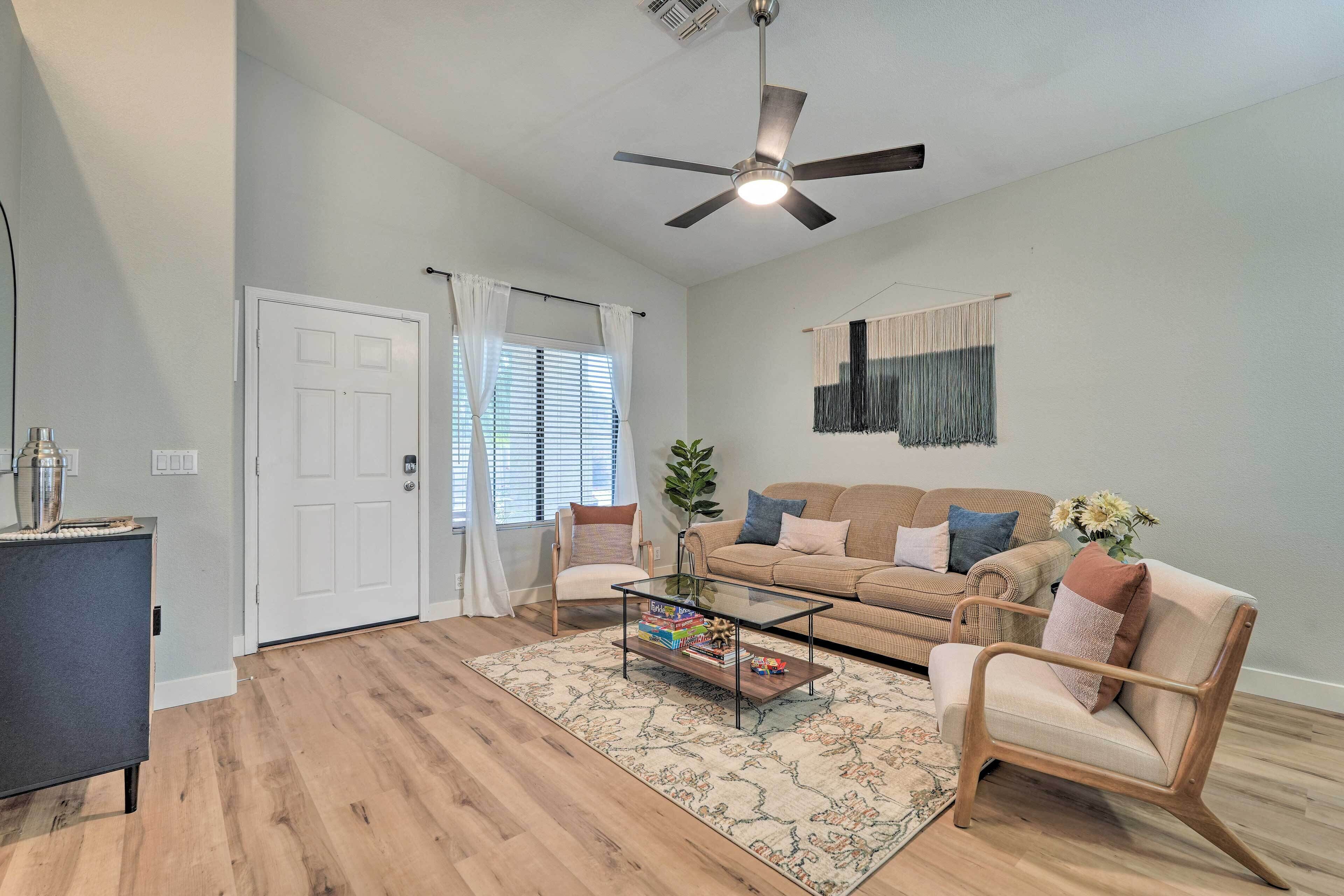 A living room with a sofa, armchairs, a coffee table, and a ceiling fan.