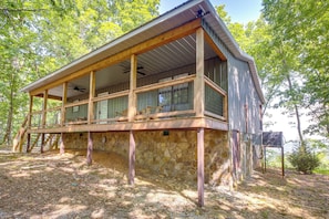 A rustic cabin with a stone foundation, wooden beams, and a balcony overlooking a forested area. - Renovated Cabin w/ Decks, Views, & Fire Pit! (Pikeville)