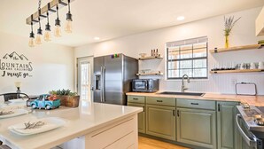A modern kitchen with a stainless steel refrigerator, microwave, and oven, wooden countertops, and green cabinets. - Renovated Cabin w/ Decks, Views, & Fire Pit! (Pikeville)
