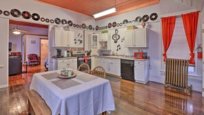A dining area with a table set for two, a kitchen with white cabinets, and a ceiling with a decorative pattern. - Upstate New York Studio Rental - Pet Friendly (Stanley)