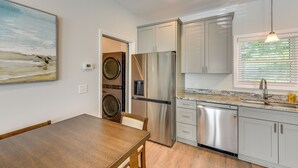 Eine moderne Küche mit Edelstahlgeräten, ein Essbereich mit einem Holztisch und ein Gemälde an der Wand.