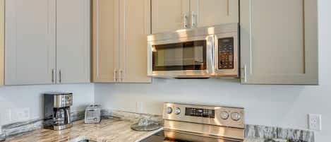 A kitchen with beige cabinets, a stainless steel microwave, a double oven, a coffee maker, and a toaster.