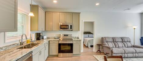 A modern kitchen with a built-in oven, microwave, and stainless steel appliances. There is a dining area with a wooden table and chairs.