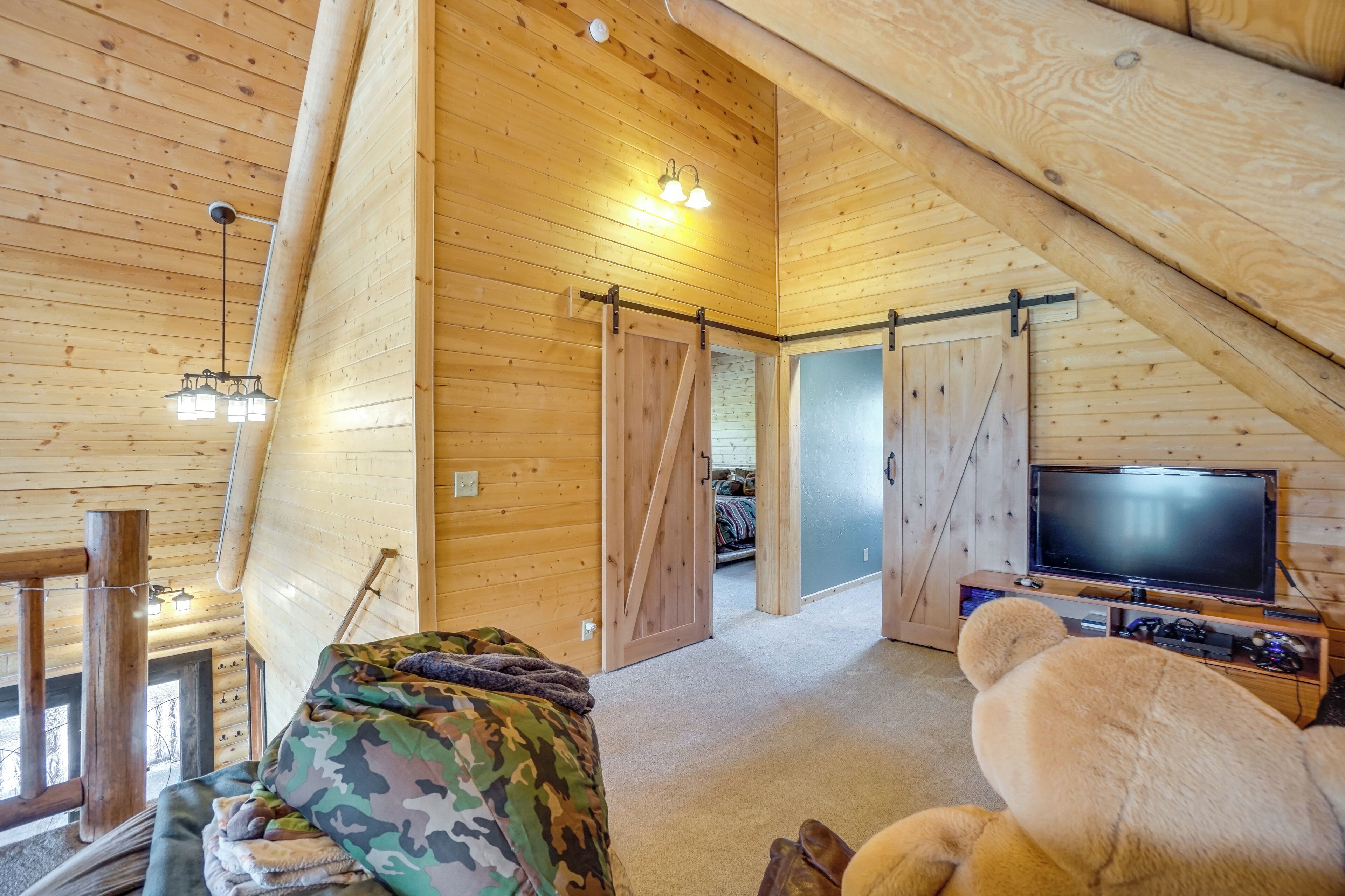A cozy cabin interior with wooden walls, a large TV, and a sliding door leading to another room.
