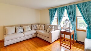 Un salon avec un canapé d’angle beige, une table basse en bois et des rideaux turquoise.