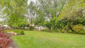 Un jardin arrière aménagé, avec une pelouse bien entretenue, un petit espace de jeux et des arbres adultes.