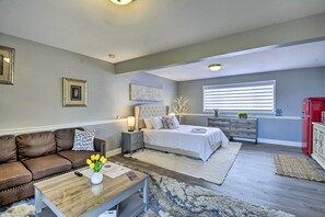 A modern bedroom with a large bed, a nightstand, a dresser, a sofa, and a coffee table. - Cozy Port Orchard Home w/ Grill & Fire Pit! (Port Orchard)