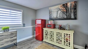 Una cocina con un refrigerador rojo, un microondas y un mueble lleno de alimentos.