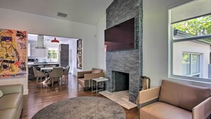 A modern living room with a fireplace, a dining area, and a kitchen in the background. - Modern Miami Villa w/ Pool Oasis ~ 5 Mi to Beach! (North Miami)