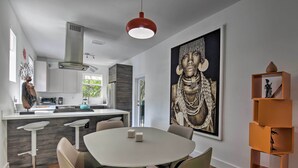 A modern kitchen with a central island, white bar stools, and a dining table with chairs. - Modern Miami Villa w/ Pool Oasis ~ 5 Mi to Beach! (North Miami)