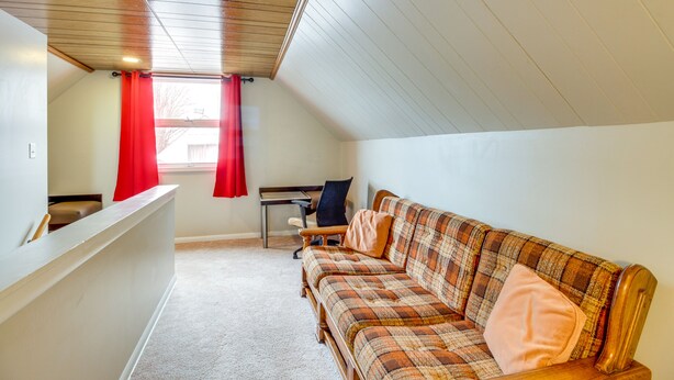 Une chambre mansardée chaleureuse, avec un canapé à carreaux, un bureau et une chaise.