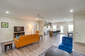 A spacious living room with a sofa, a blue armchair, and a TV. - Quaint Harrison Home 2 Mi to Downtown! (Harrison)