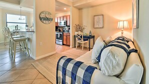 A living room with a couch, a dining area with chairs, a kitchen in the background, and a wall clock. - Screened Patio & Resort Perks: Bradenton Condo! (Bradenton)