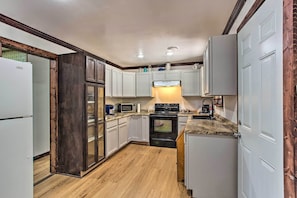 A compact kitchen with white cabinets, a black stove, and a microwave. - Lovely 'anna Fink House' w/ Patio & Fire Pit (Atoka)
