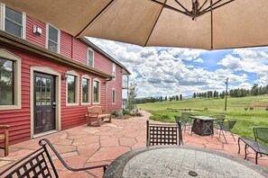 A red house with a patio, outdoor seating, and a view of a green field. - Mtn View + Group Ready: Conifer Home on 100 Acres! (Conifer)
