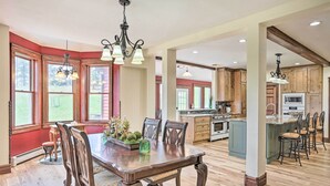 A spacious kitchen with wooden cabinets, a central island, and a dining area with a large wooden table and chairs. - Mtn View + Group Ready: Conifer Home on 100 Acres! (Conifer)