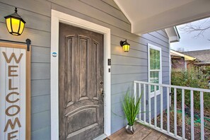 A house entrance with a dark wooden door, a welcome sign, and two wall-mounted lights.