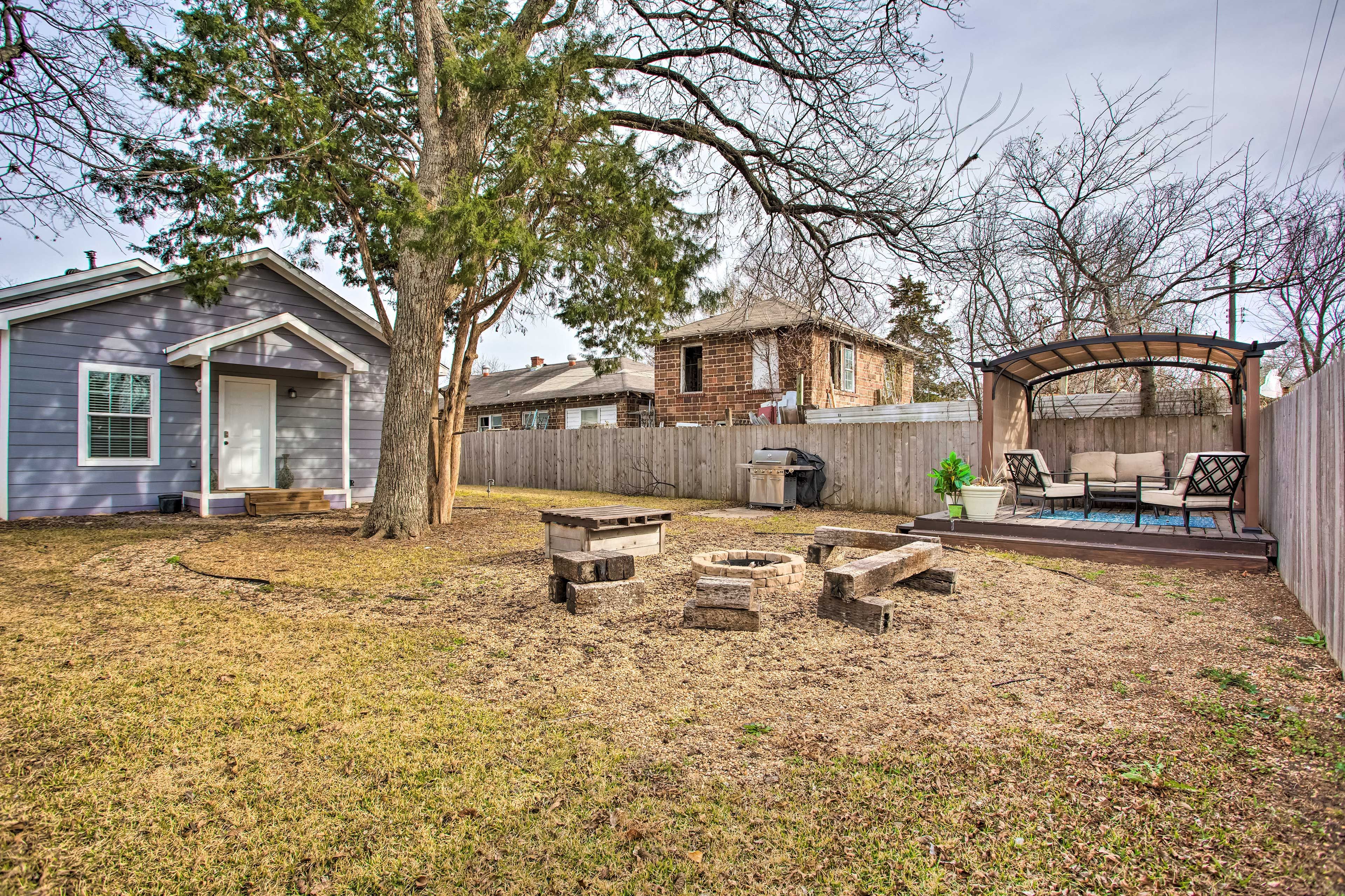 A backyard with a wooden deck, a fire pit, and a barbecue area.