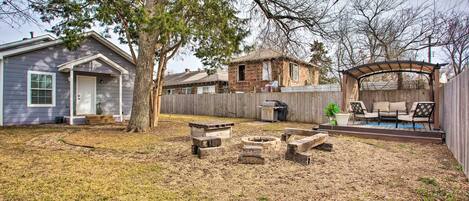A backyard with a wooden deck, a fire pit, and a barbecue area.