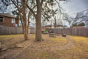 Un jardin avec une clôture en bois, un patio couvert et un arbre.