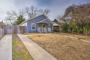 A single-story house with a front porch, a wooden fence, and a well-maintained lawn.