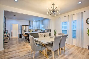 A modern kitchen with white cabinets, a central island, and a dining area with a light-colored table and grey chairs. - 4 Mi to Dtwn Dallas: Home w/ Fire Pit + Gazebo (Dallas)