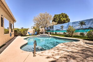A swimming pool with a curved edge, a metal ladder, and a clear blue sky. - Sun-drenched Home w/ Private Pool in Goodyear (Goodyear)