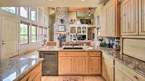 A spacious kitchen with granite countertops, wooden cabinets, and a stone fireplace.