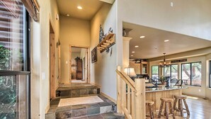 A spacious kitchen with a bar area, stone steps leading to a second floor, and large windows offering views of the outdoors.