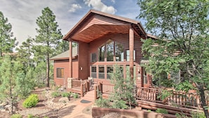 A log cabin with a porch, large windows, and a stone pathway leading to the entrance.