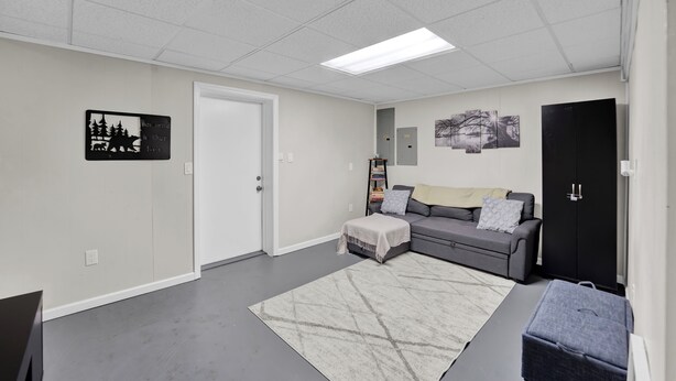 A room with a grey sofa, a white rug, a black cabinet, and a door. - Poconos Retreat w/ Pool and Lake Access (Lake Ariel)
