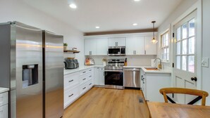 Una cocina moderna con armarios blancos, electrodomésticos de acero inoxidable y una mesa de comedor de madera.