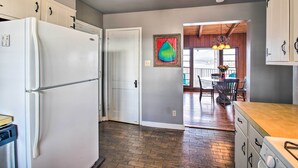 A kitchen with a refrigerator, cabinets, and a dining area with a table and chairs.