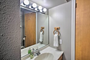 A bathroom with a large mirror, a sink, and two towel rings.