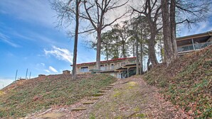 A hillside with a building with a red roof and a balcony.